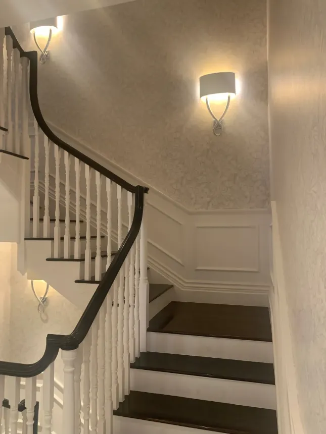 white staircase with dark rail and wallpaper on the wall